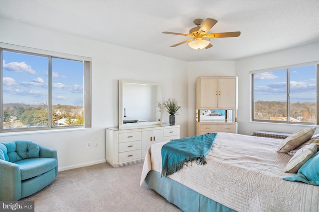 bedroom featuring baseboards, ceiling fan, multiple windows, and light colored carpet