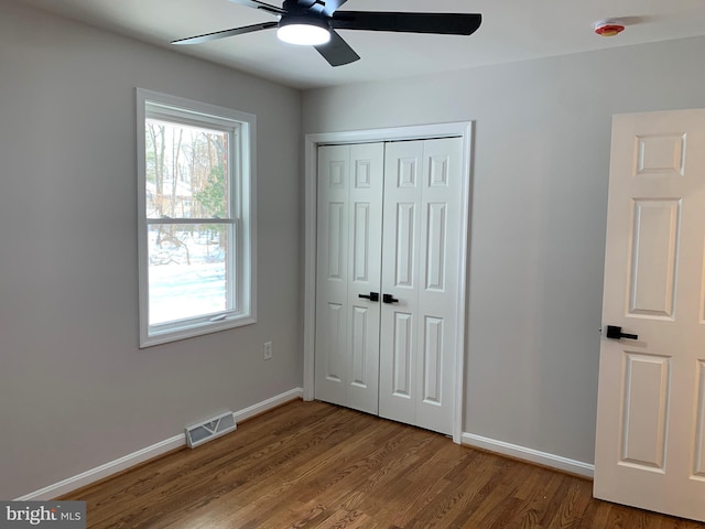 unfurnished bedroom featuring baseboards, visible vents, a ceiling fan, wood finished floors, and a closet