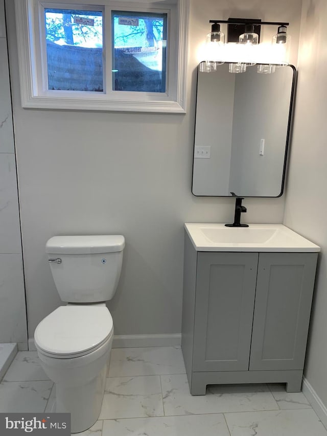 bathroom with toilet, marble finish floor, baseboards, and vanity