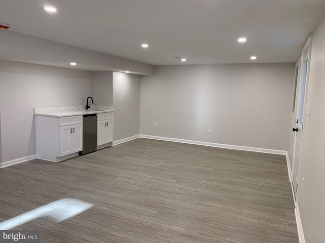 bar with recessed lighting, a sink, wood finished floors, baseboards, and stainless steel dishwasher