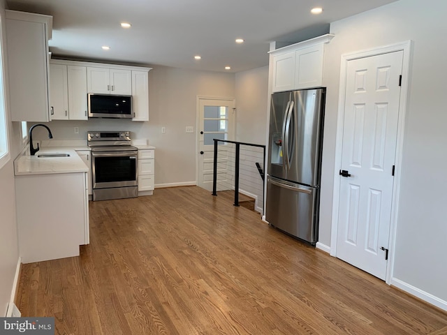 kitchen with light countertops, appliances with stainless steel finishes, a sink, and light wood-style floors