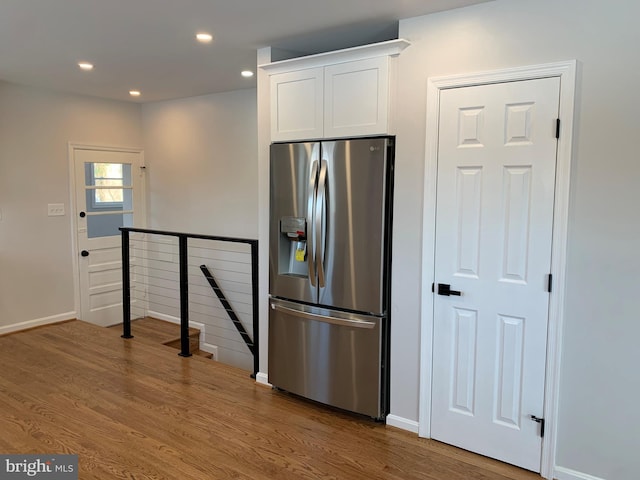 kitchen with stainless steel fridge, white cabinetry, wood finished floors, and recessed lighting