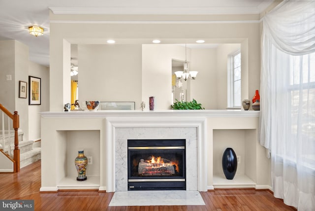 interior details with hardwood / wood-style flooring, crown molding, a notable chandelier, and a high end fireplace