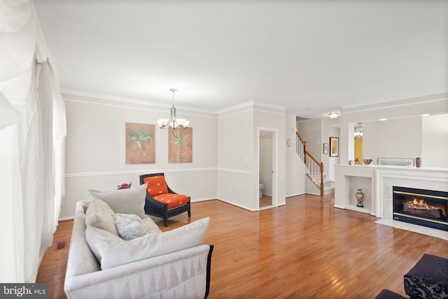 living room featuring an inviting chandelier, crown molding, and light hardwood / wood-style flooring