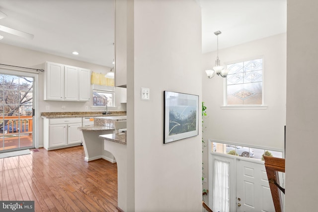 foyer entrance featuring an inviting chandelier, sink, and light hardwood / wood-style flooring