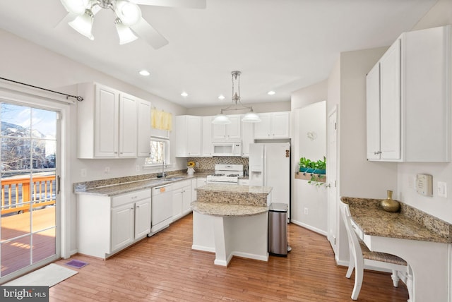 kitchen with sink, white appliances, hanging light fixtures, a center island, and white cabinets