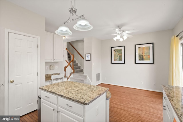 kitchen with white cabinetry, hanging light fixtures, light wood-type flooring, and a kitchen island