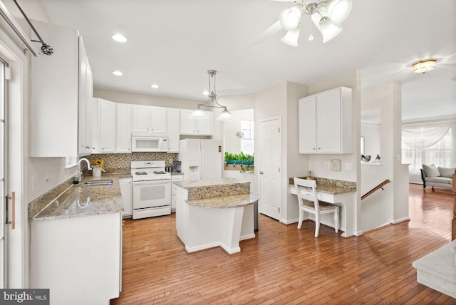 kitchen with a center island, sink, white cabinets, and white appliances