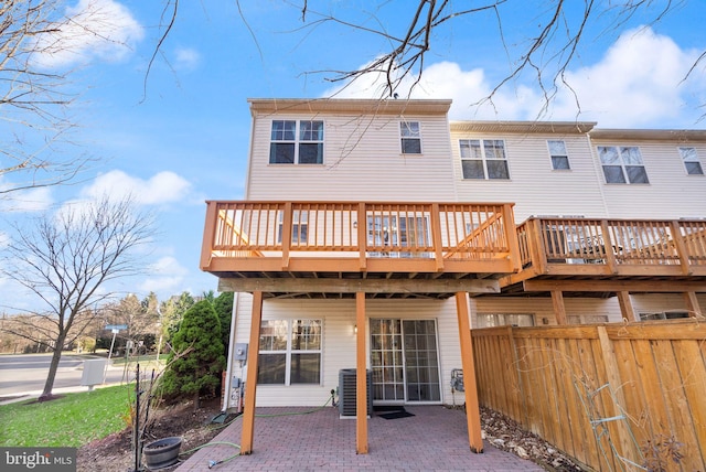 back of property with central AC, a deck, and a patio