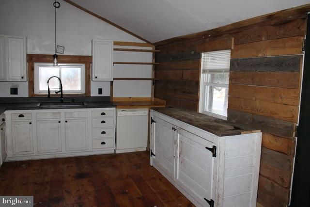 kitchen featuring white cabinetry, dishwasher, vaulted ceiling, pendant lighting, and sink