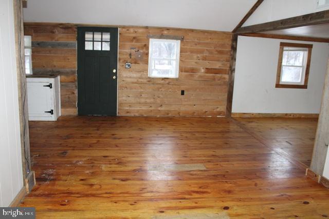 entrance foyer featuring vaulted ceiling with beams, hardwood / wood-style floors, and wooden walls