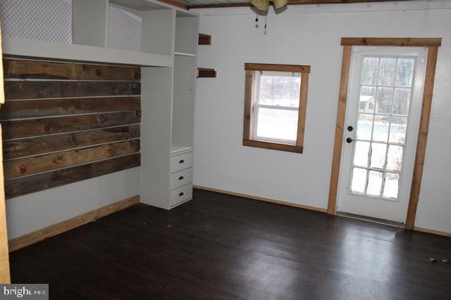 unfurnished bedroom with dark wood-type flooring and multiple windows