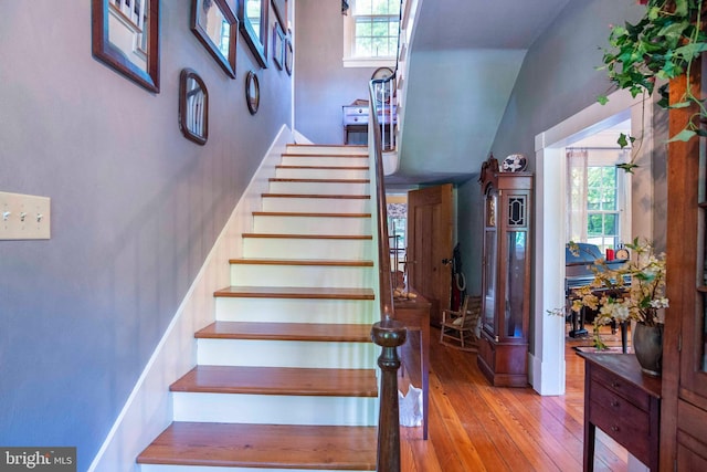 staircase with a towering ceiling and wood-type flooring