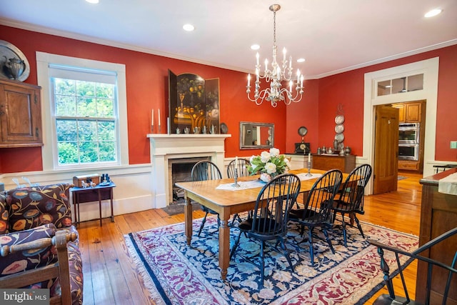 dining room featuring light wood-type flooring, an inviting chandelier, and crown molding