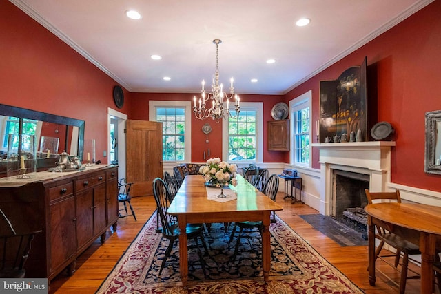 dining space featuring light wood-type flooring, crown molding, and a notable chandelier