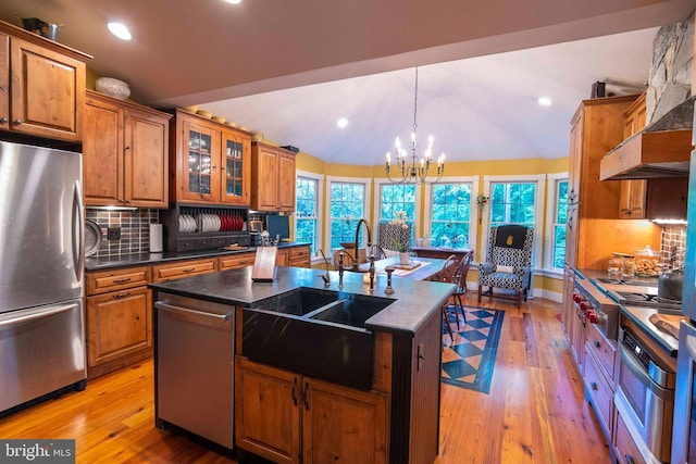 kitchen featuring appliances with stainless steel finishes, sink, backsplash, a chandelier, and a center island with sink