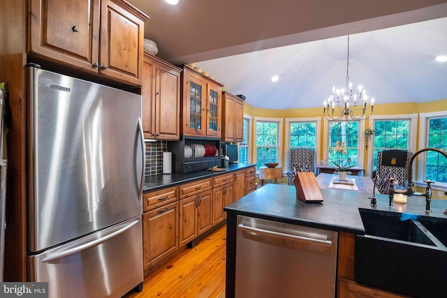 kitchen with tasteful backsplash, vaulted ceiling, a notable chandelier, sink, and stainless steel appliances