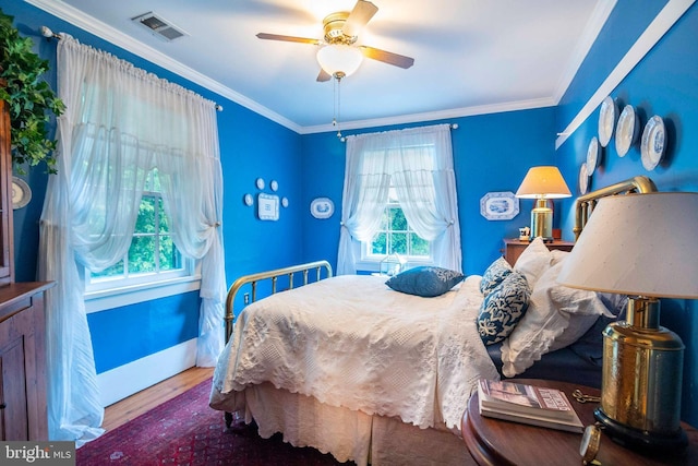 bedroom featuring ceiling fan, multiple windows, hardwood / wood-style floors, and crown molding