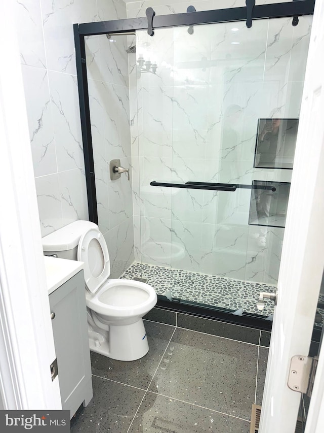 bathroom featuring toilet, tile patterned flooring, walk in shower, and vanity