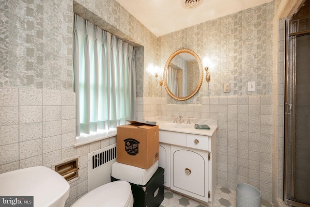 bathroom featuring an enclosed shower, radiator heating unit, vanity, tile walls, and toilet