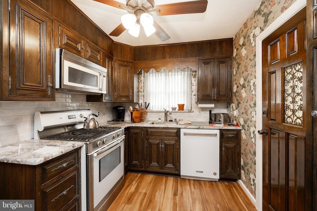 kitchen featuring tasteful backsplash, light hardwood / wood-style floors, sink, stainless steel appliances, and light stone counters