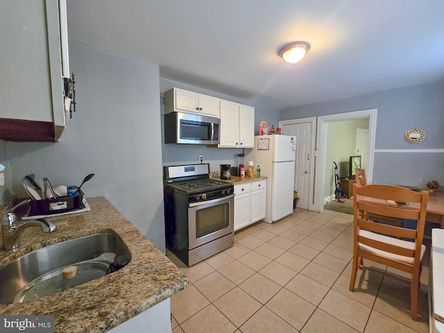 kitchen with light tile patterned floors, stainless steel appliances, white cabinets, and sink