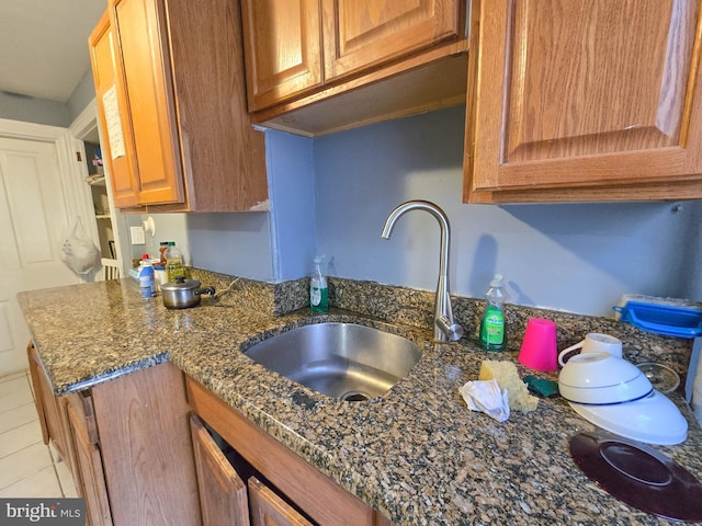 kitchen featuring sink, light tile patterned floors, and dark stone counters