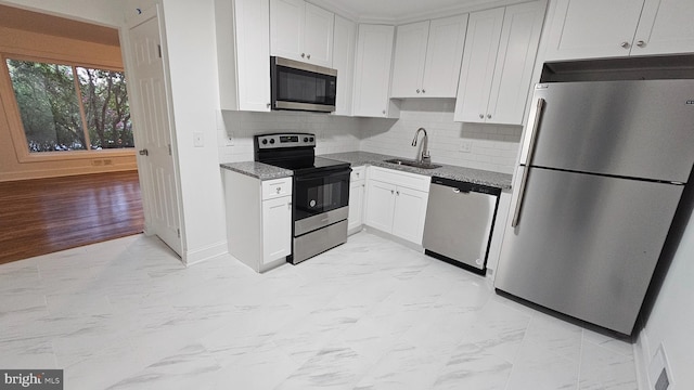 kitchen featuring appliances with stainless steel finishes, dark stone countertops, white cabinets, and sink