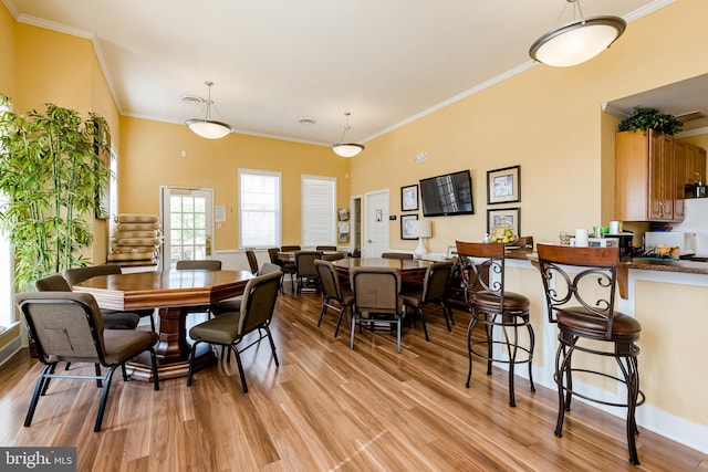 dining space with crown molding and light wood-type flooring