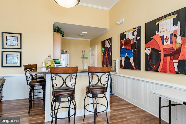 kitchen featuring crown molding, a kitchen bar, kitchen peninsula, and hardwood / wood-style flooring