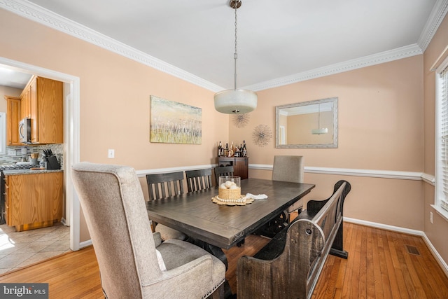 dining space featuring light wood-type flooring and crown molding