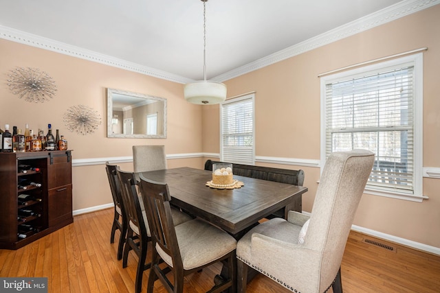 dining room featuring crown molding and light hardwood / wood-style flooring