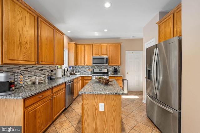 kitchen with stone counters, appliances with stainless steel finishes, backsplash, and a kitchen island