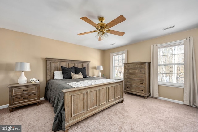 bedroom with ceiling fan, multiple windows, and light carpet