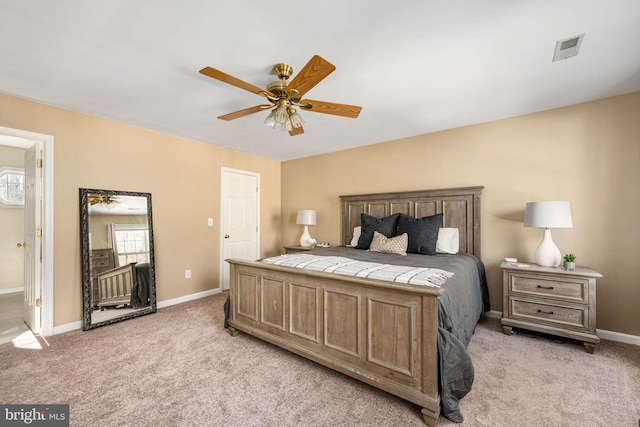 bedroom with ceiling fan, light colored carpet, and ensuite bathroom