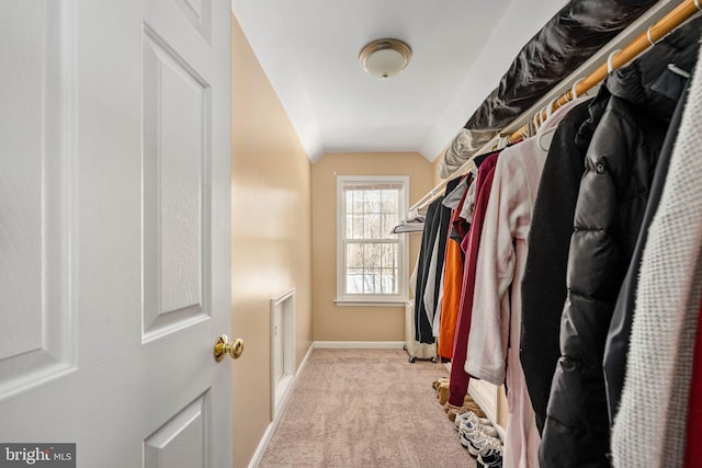 spacious closet with light colored carpet and vaulted ceiling