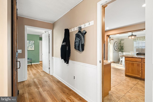 corridor with light hardwood / wood-style flooring and crown molding