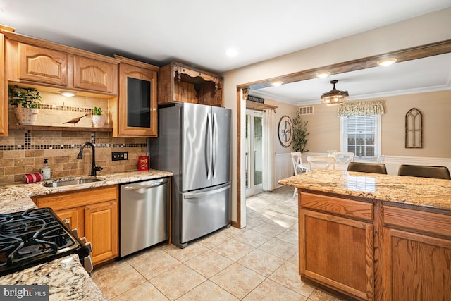 kitchen with appliances with stainless steel finishes, sink, light tile patterned flooring, light stone countertops, and ornamental molding