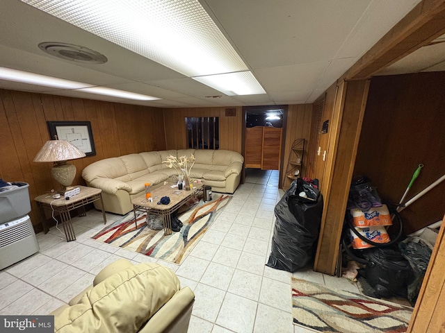 living room with a drop ceiling and wood walls