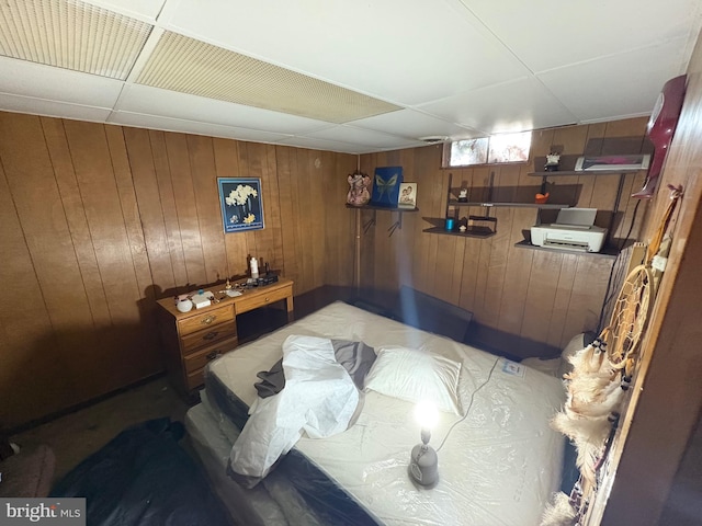 bedroom featuring a drop ceiling and wooden walls