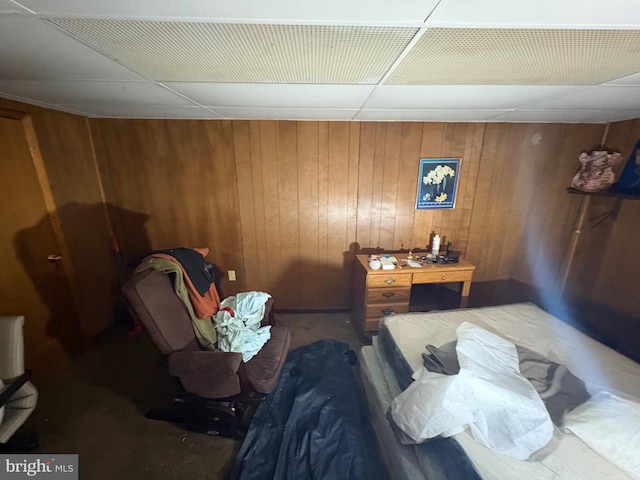 bedroom featuring a paneled ceiling and wooden walls