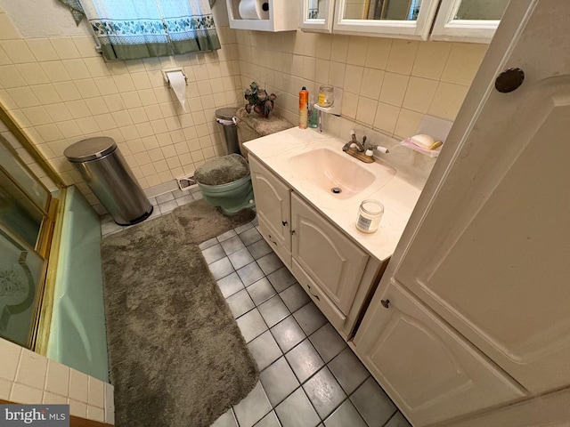 bathroom with toilet, vanity, tile patterned flooring, and tile walls