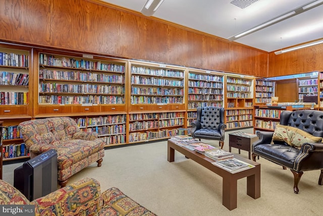 sitting room with carpet floors and wood walls