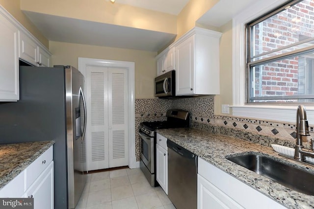 kitchen featuring backsplash, sink, stainless steel appliances, white cabinets, and light stone counters