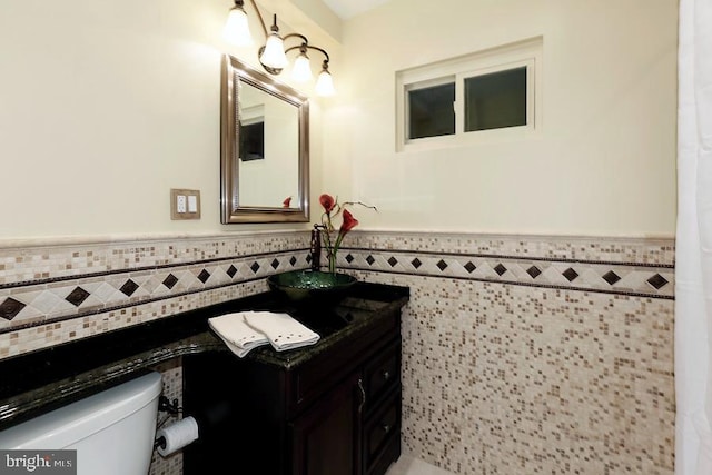 bathroom featuring toilet, vanity, and tile walls