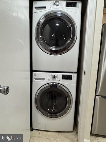 laundry area featuring light tile patterned flooring and stacked washer and clothes dryer