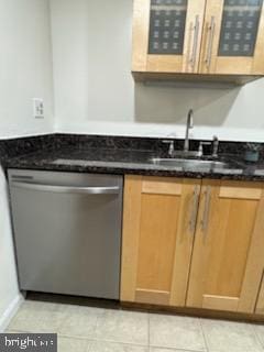 kitchen with sink, light tile patterned floors, dark stone counters, and dishwasher