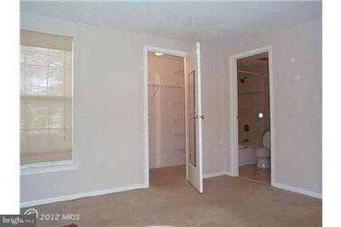 unfurnished bedroom featuring ensuite bathroom, a spacious closet, and a closet