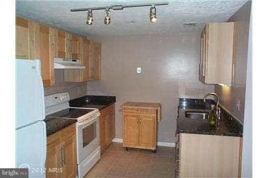 kitchen featuring sink, white appliances, a textured ceiling, and light tile patterned flooring