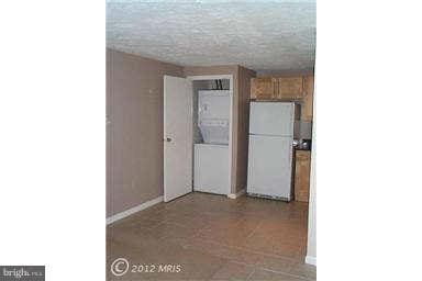 kitchen with white refrigerator and stacked washing maching and dryer